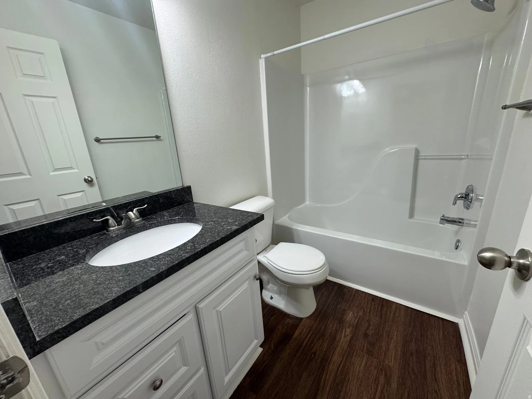 Bathroom featuring a white vanity with cabinet storage, dark stone countertop, and an oval undermount sink