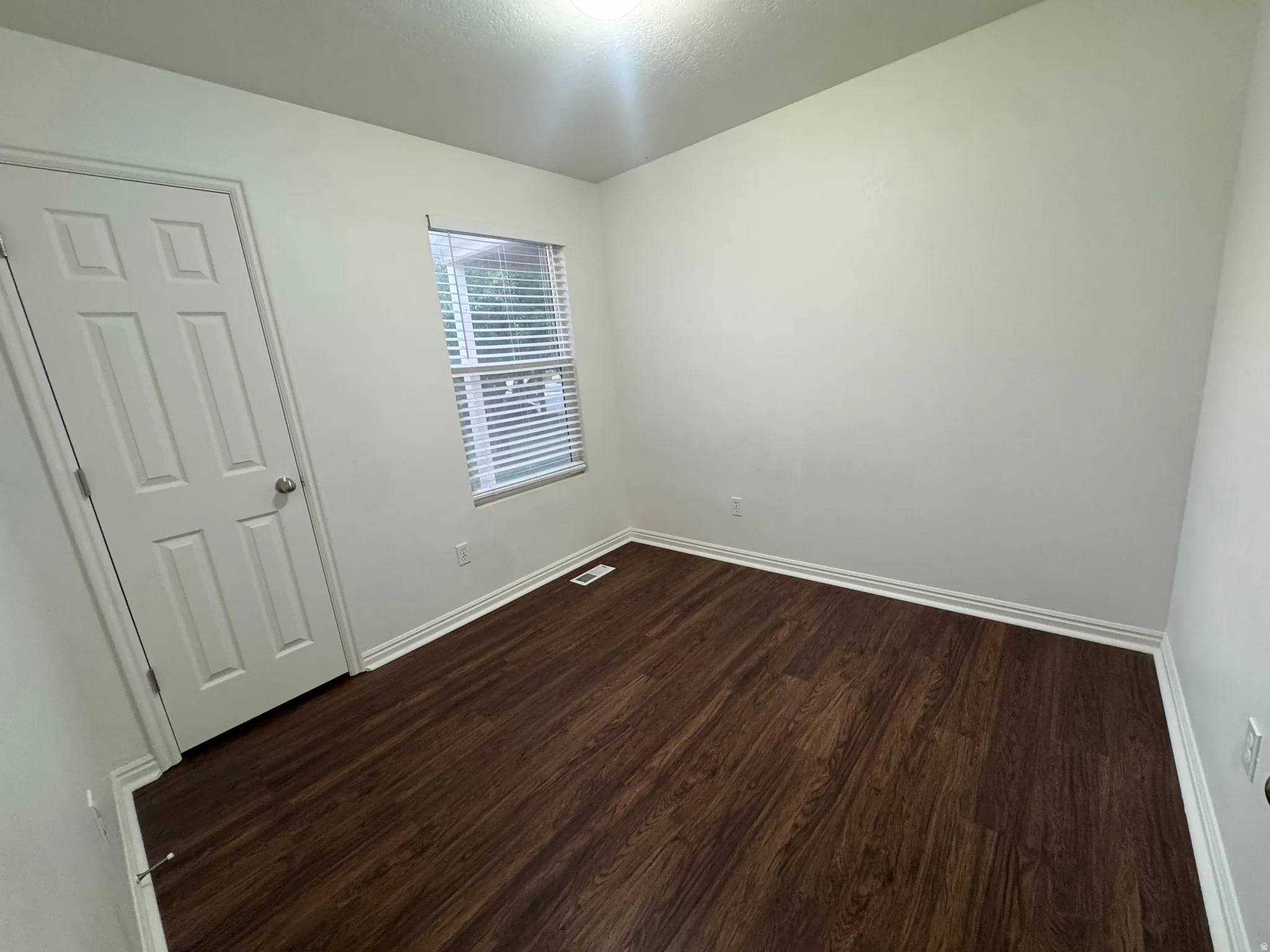 Room featuring wood-finish flooring, white baseboards, and neutral wall tones