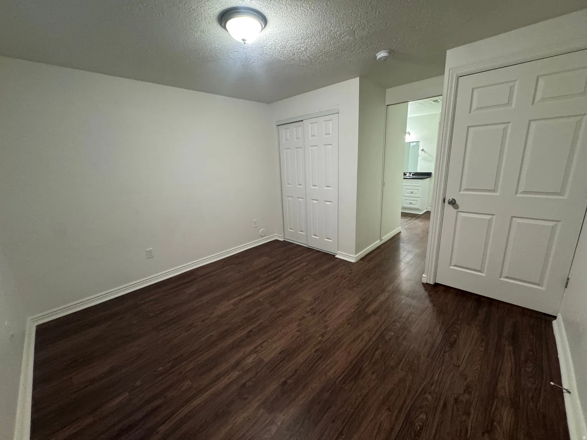 Room featuring wood-finish flooring, white baseboards, and a flush-mount ceiling light