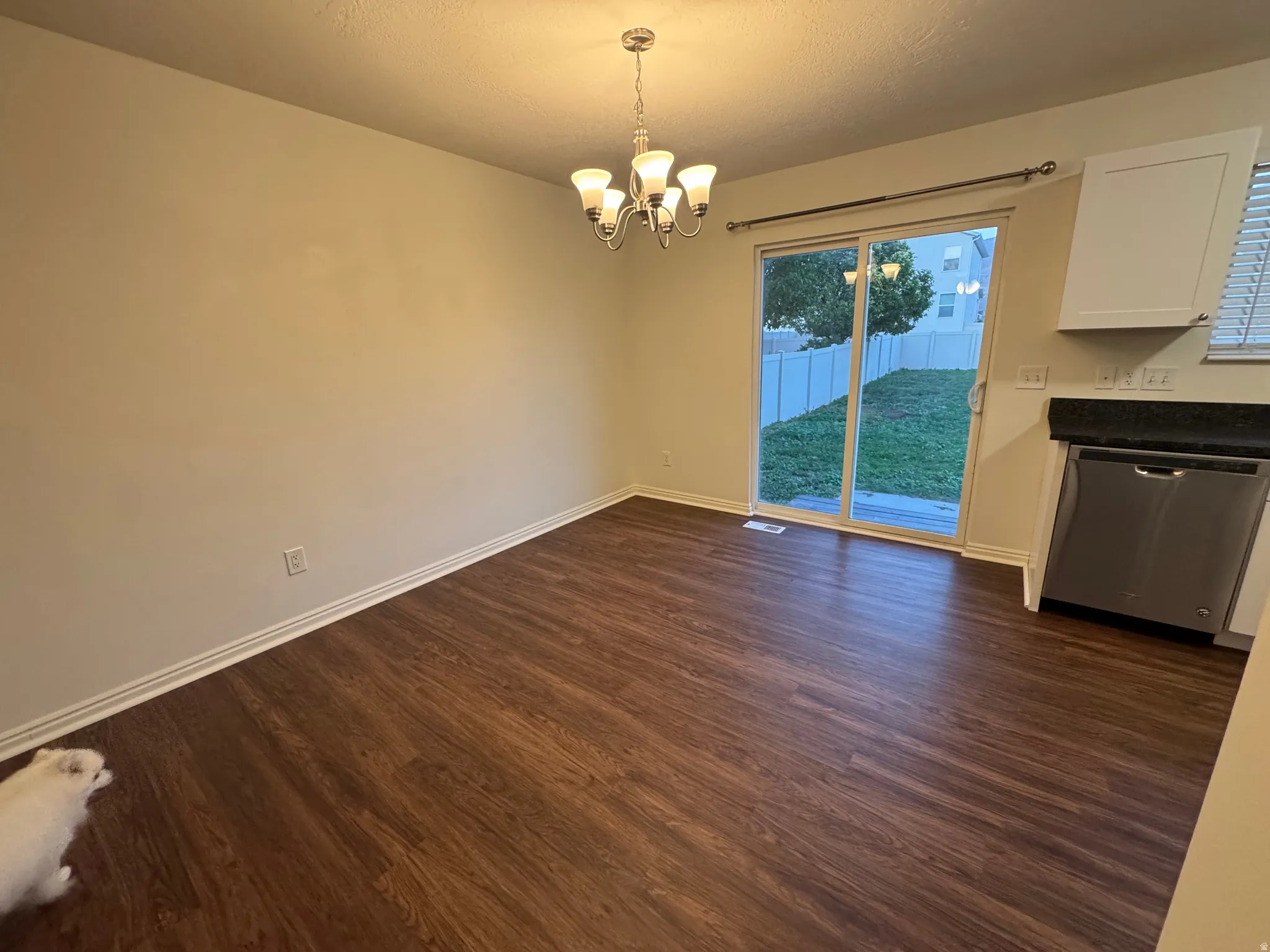 Dining area featuring wood-finish flooring, a contemporary chandelier, and direct patio access through sliding glass doors