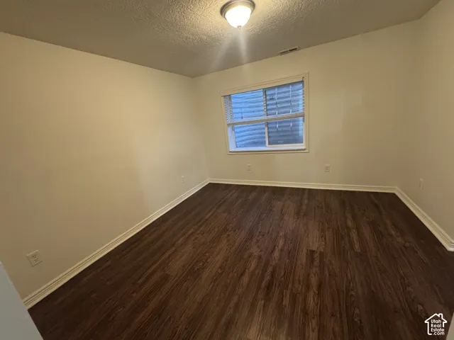 Room featuring wood-finish flooring, neutral wall paint, white trim, a single window with blinds, and an overhead flush-mount light fixture