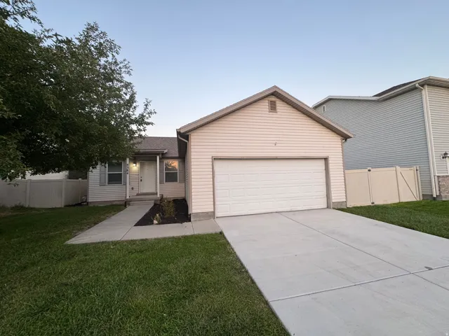 Single-story residence featuring light-colored siding, an attached garage, and a concrete driveway