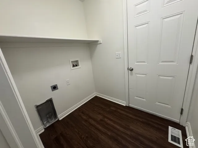 Dedicated laundry area featuring a white storage shelf, white paneled door, and dark wood-finish flooring