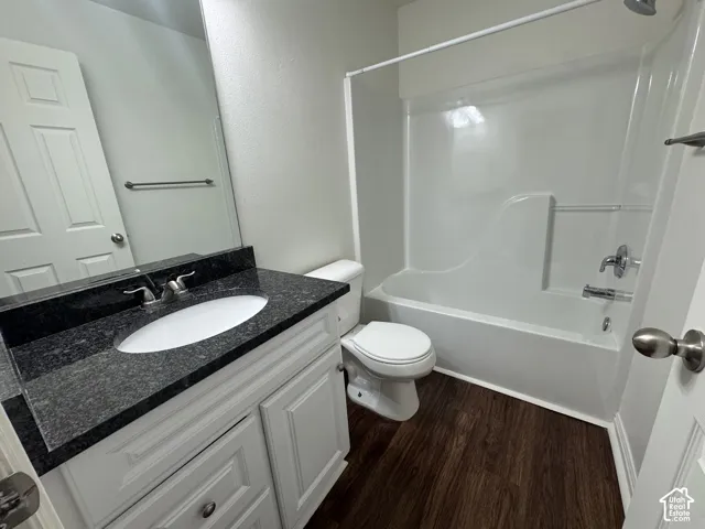 Bathroom featuring a white vanity with cabinet storage, dark stone countertop, and an oval undermount sink