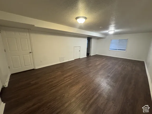 Spacious room featuring wood-finish flooring, white walls, and a visible window