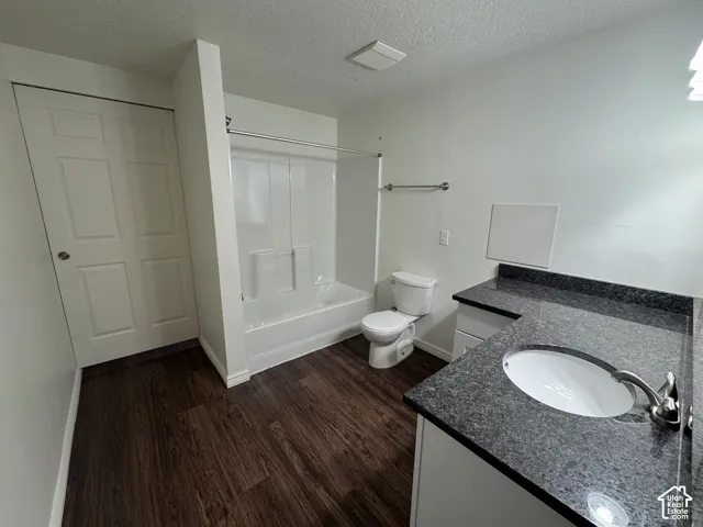 Bathroom featuring wood-finish flooring and a white vanity with a dark speckled countertop