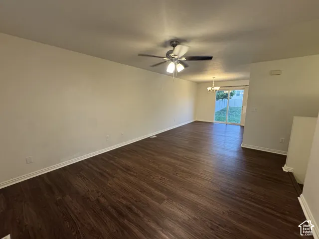 Spacious living area featuring wood-finish flooring, a ceiling fan with integrated lighting, and neutral wall tones