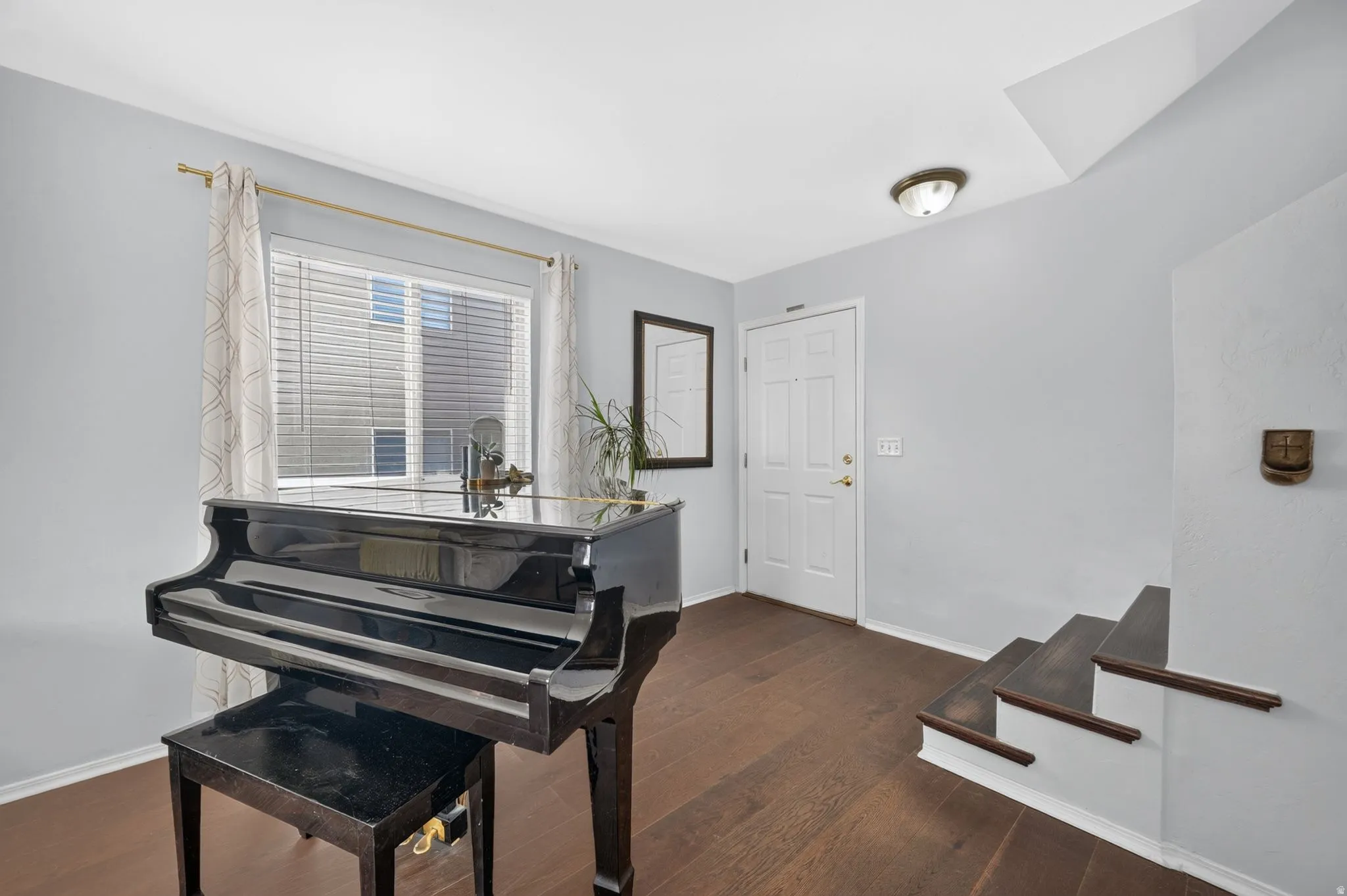 Entryway featuring dark wood-finish flooring, a white paneled door, and a staircase with dark treads and white risers