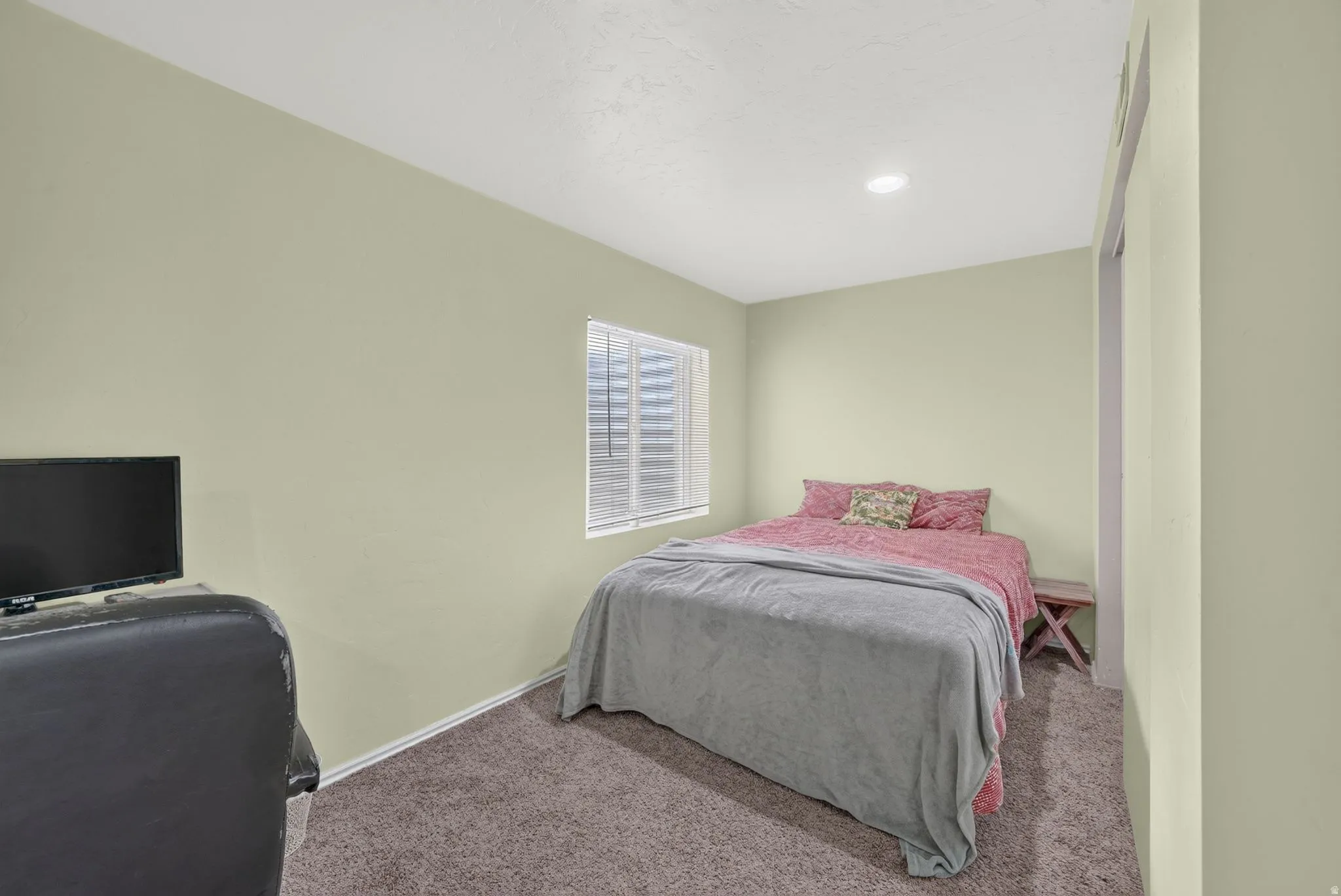 Carpeted room featuring a single window with blinds, recessed ceiling lighting, and light-toned walls
