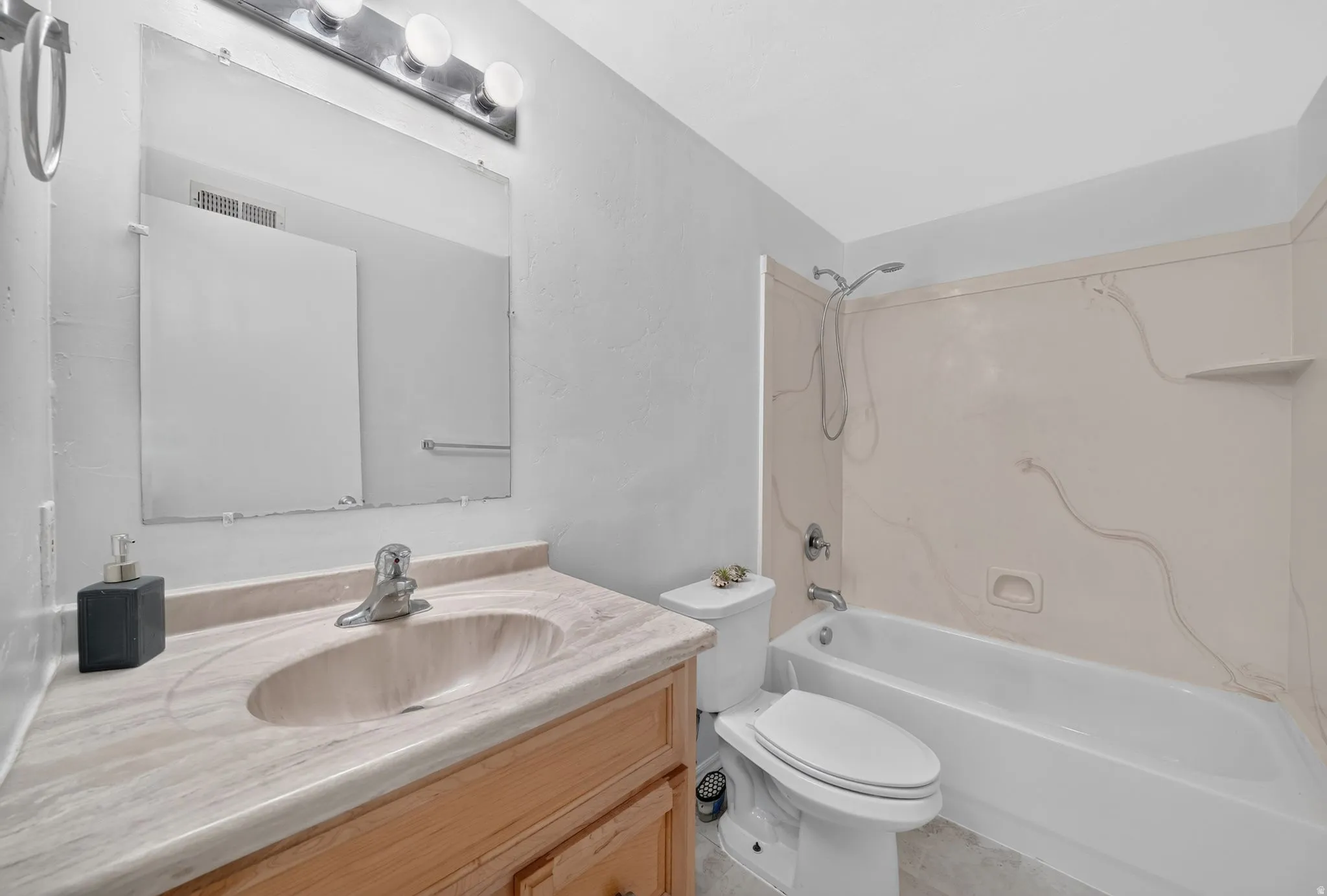 Bathroom vanity featuring an integrated sink, wood-finish cabinetry, and a full-width wall mirror