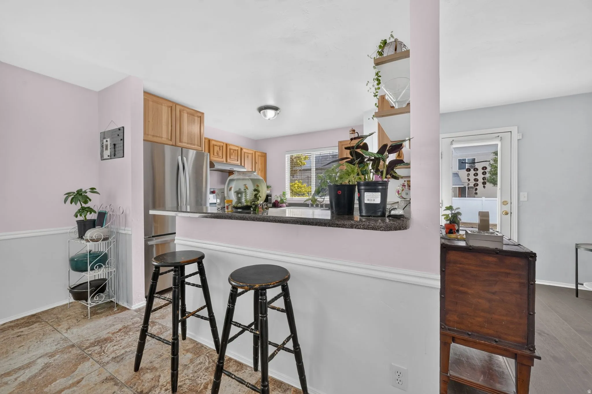 Kitchen pass-through featuring a dark countertop, light wood cabinetry, and stainless steel appliances