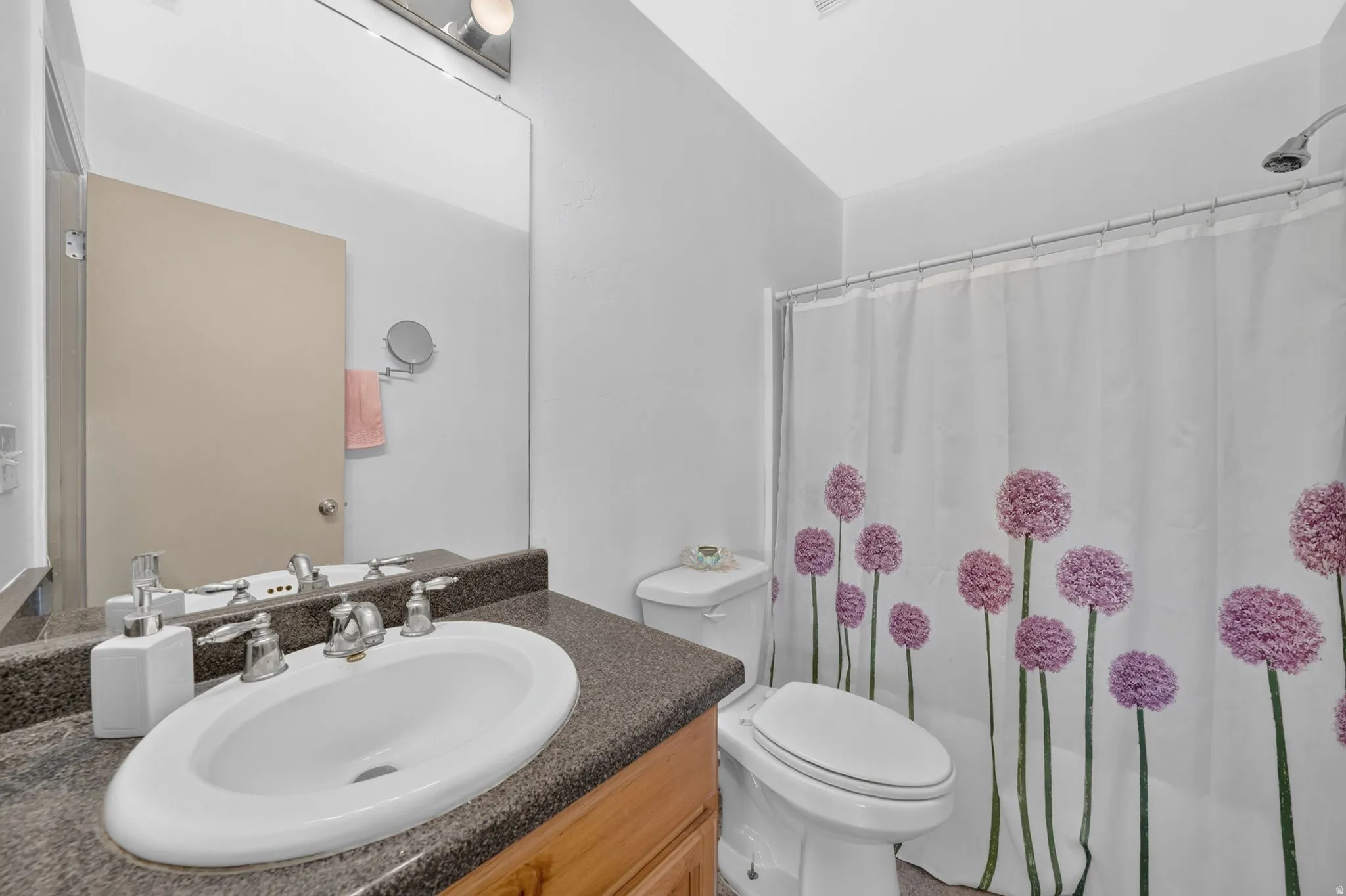 Bathroom featuring a vanity with a white oval sink, chrome fixtures, and a dark speckled countertop