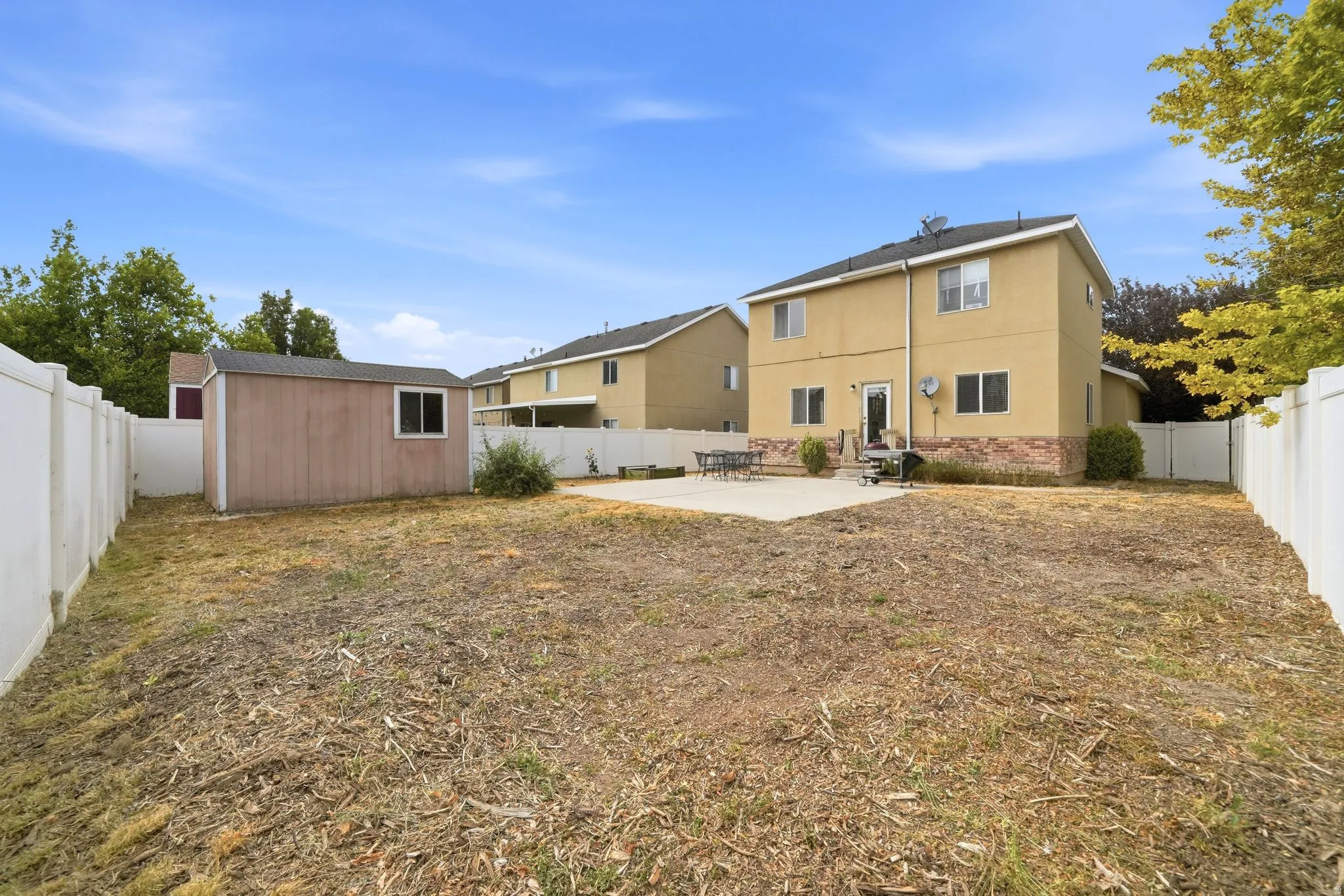 Spacious backyard featuring a storage shed, concrete patio, and full perimeter fencing