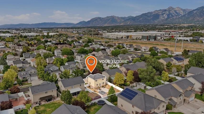 Aerial perspective showcasing a residential property with a light-colored exterior and a dark roof, situated within a neighborhood featuring mature trees and established homes