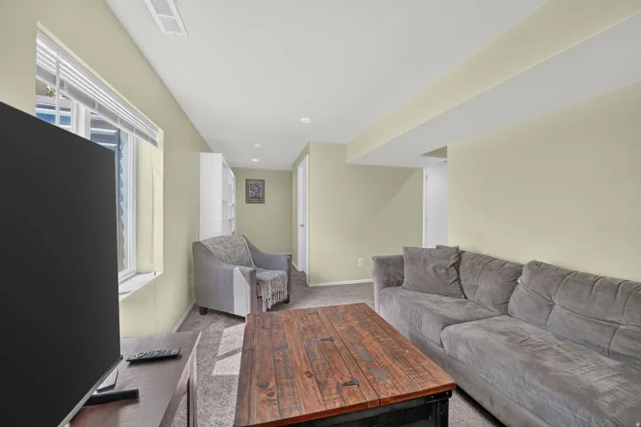 Carpeted living space with recessed lighting, a window featuring blinds, and a built-in shelving unit