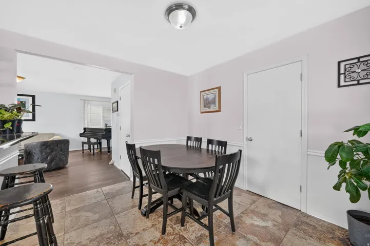 Dining area with neutral wall color, white wainscoting, and tile flooring