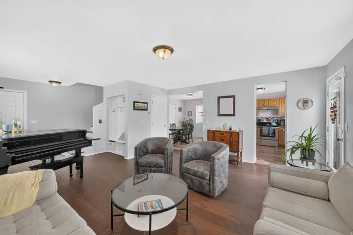 Spacious living area featuring rich wood-finish flooring, light gray wall paint, and a built-in coat nook