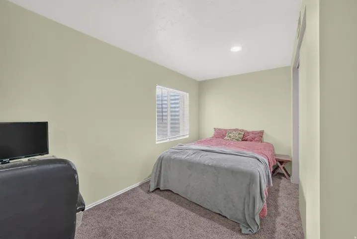 Carpeted room featuring a single window with blinds, recessed ceiling lighting, and light-toned walls