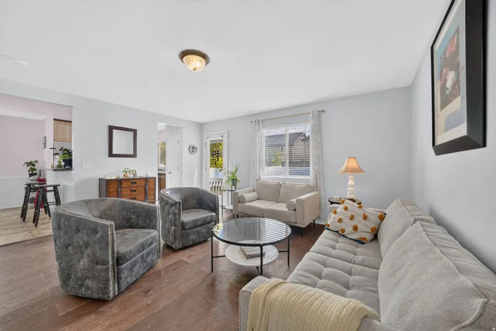Spacious living area featuring wood-finish flooring, ample natural light from a window with blinds, and recessed lighting