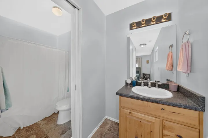 Bathroom featuring a wood-finish vanity with a built-in sink and dark countertop