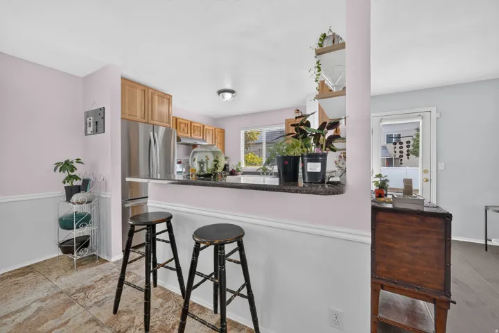 Kitchen pass-through featuring a dark countertop, light wood cabinetry, and stainless steel appliances