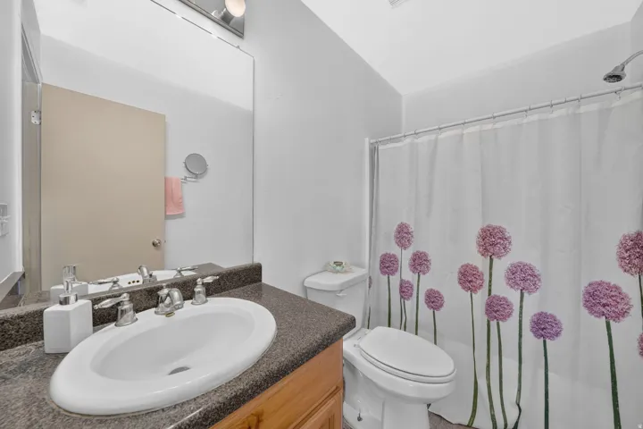 Bathroom featuring a vanity with a white oval sink, chrome fixtures, and a dark speckled countertop