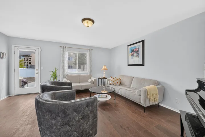 Living area featuring wood-finish flooring, light-toned walls, and a glass-paneled exterior door