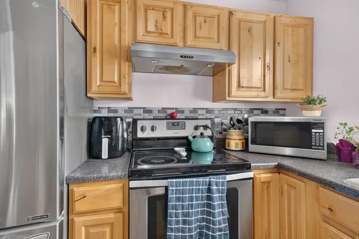 Kitchen featuring light wood cabinetry, dark speckled countertops, and a tiled backsplash