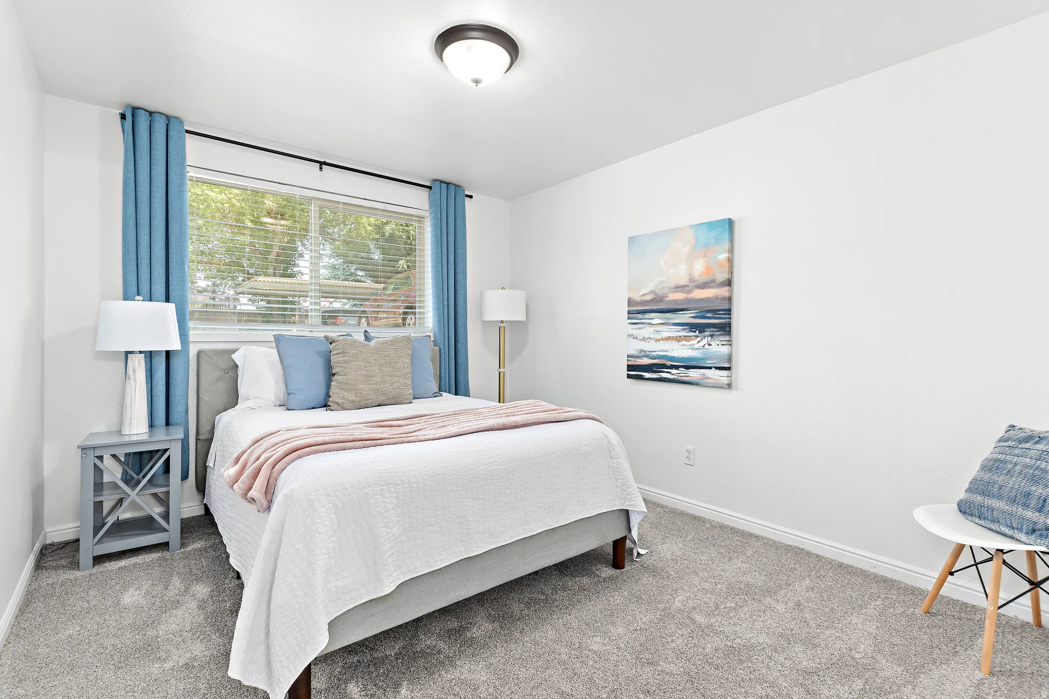 Bedroom featuring light-toned carpet flooring, a large window with blinds, and white wall finishes