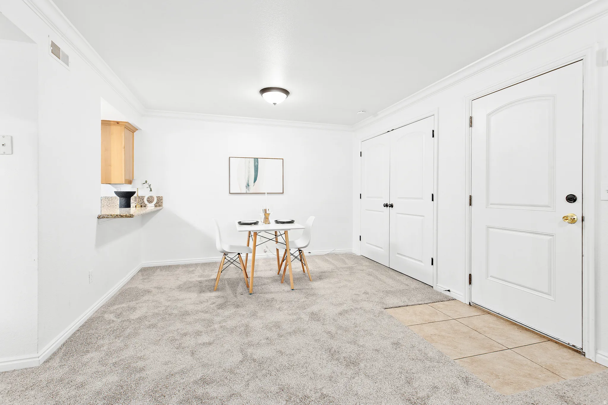 Bright interior space featuring light-colored carpeting, white baseboards, and crown molding