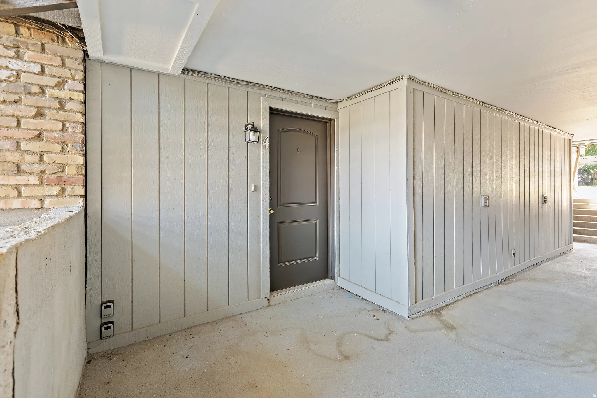 Exterior entry featuring a paneled door with hardware, an overhead light fixture, and vertical plank siding
