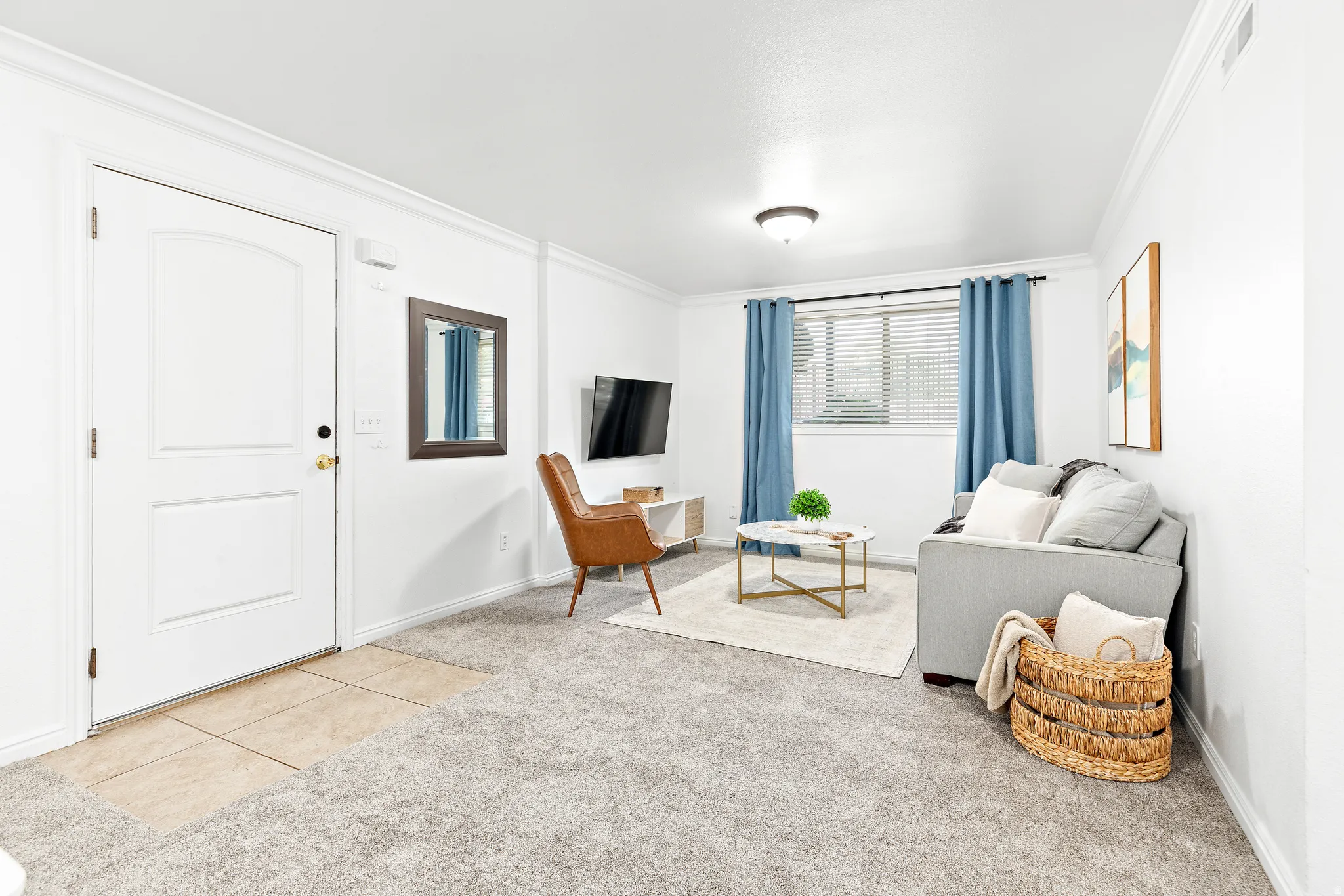 Living area featuring crown molding, neutral carpeting, and a window with blinds