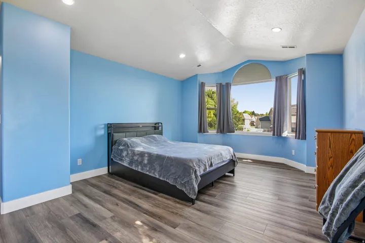 Spacious room featuring wood-finish flooring, recessed lighting, and a prominent bay window with an arched transom