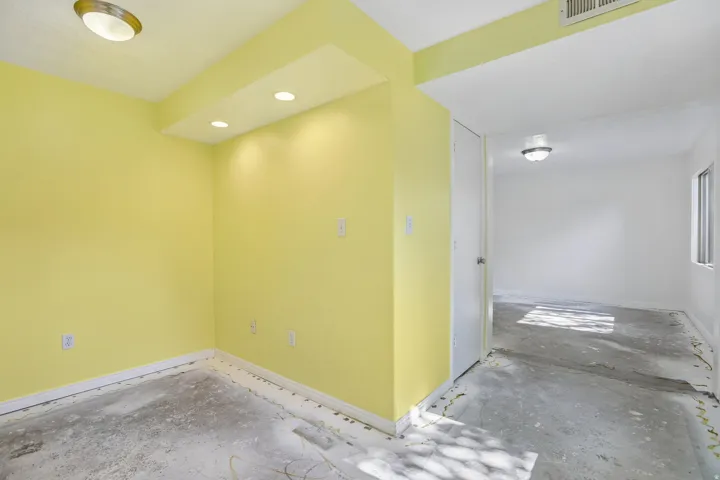 Interior space with bright yellow walls, recessed lighting, and a white baseboard trim