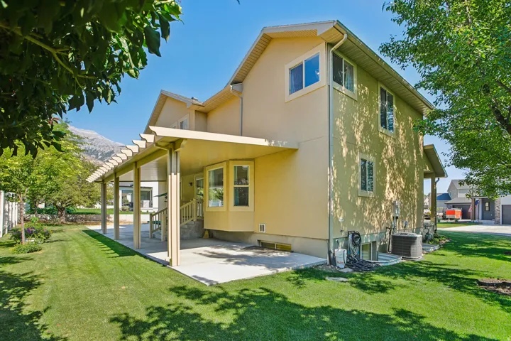 Two-story stucco exterior with multiple windows and a covered patio featuring a pergola