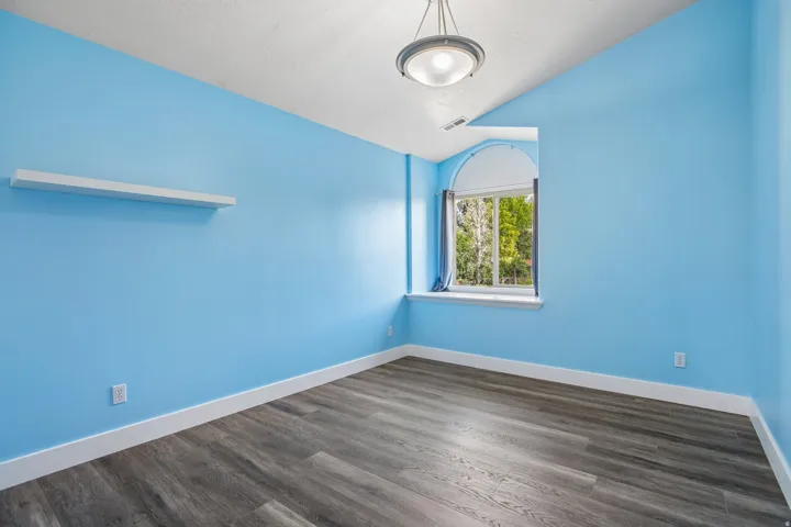 Interior space featuring wood-finish flooring, a vaulted ceiling, and an arched window with a deep sill