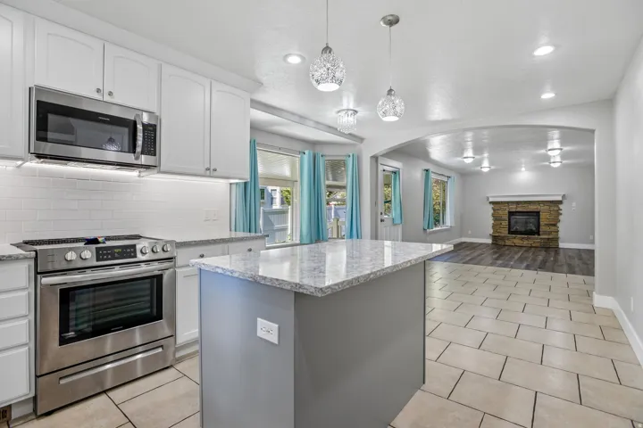 Kitchen featuring white cabinetry, stainless steel appliances, a subway tile backsplash, and a central island with a granite countertop