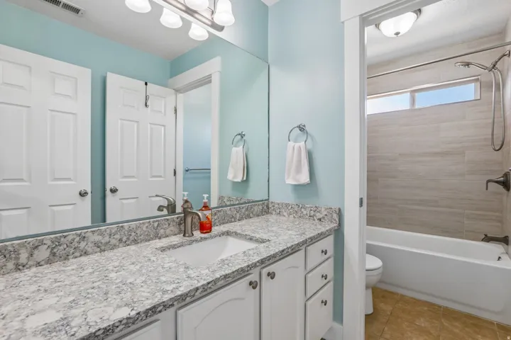 Bathroom featuring a single vanity with granite-patterned countertop, white cabinetry, and an undermount sink