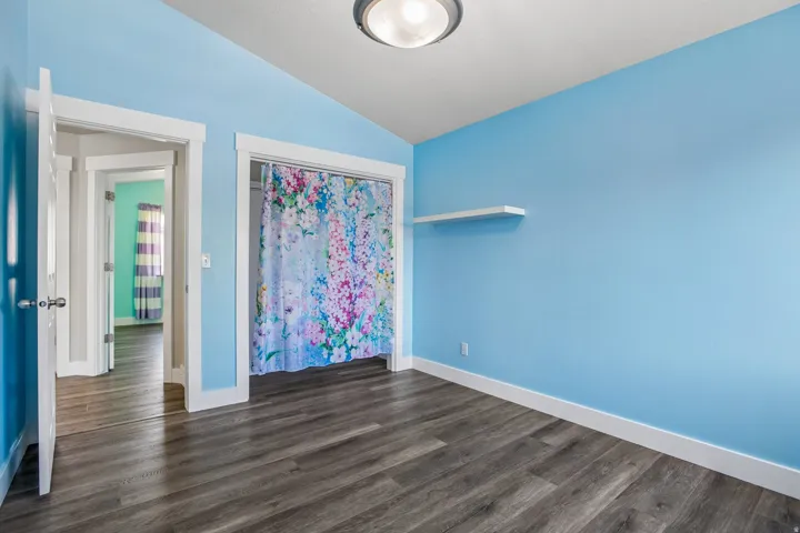 Room featuring wood-finish flooring, a vaulted ceiling, and ample natural light