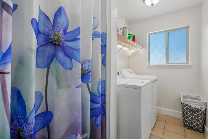 Dedicated laundry area featuring a tile floor, white walls, and a single window with a white frame