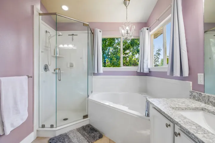 Contemporary bathroom featuring a corner glass-enclosed shower, a separate soaking tub, and a vanity with a single undermount sink
