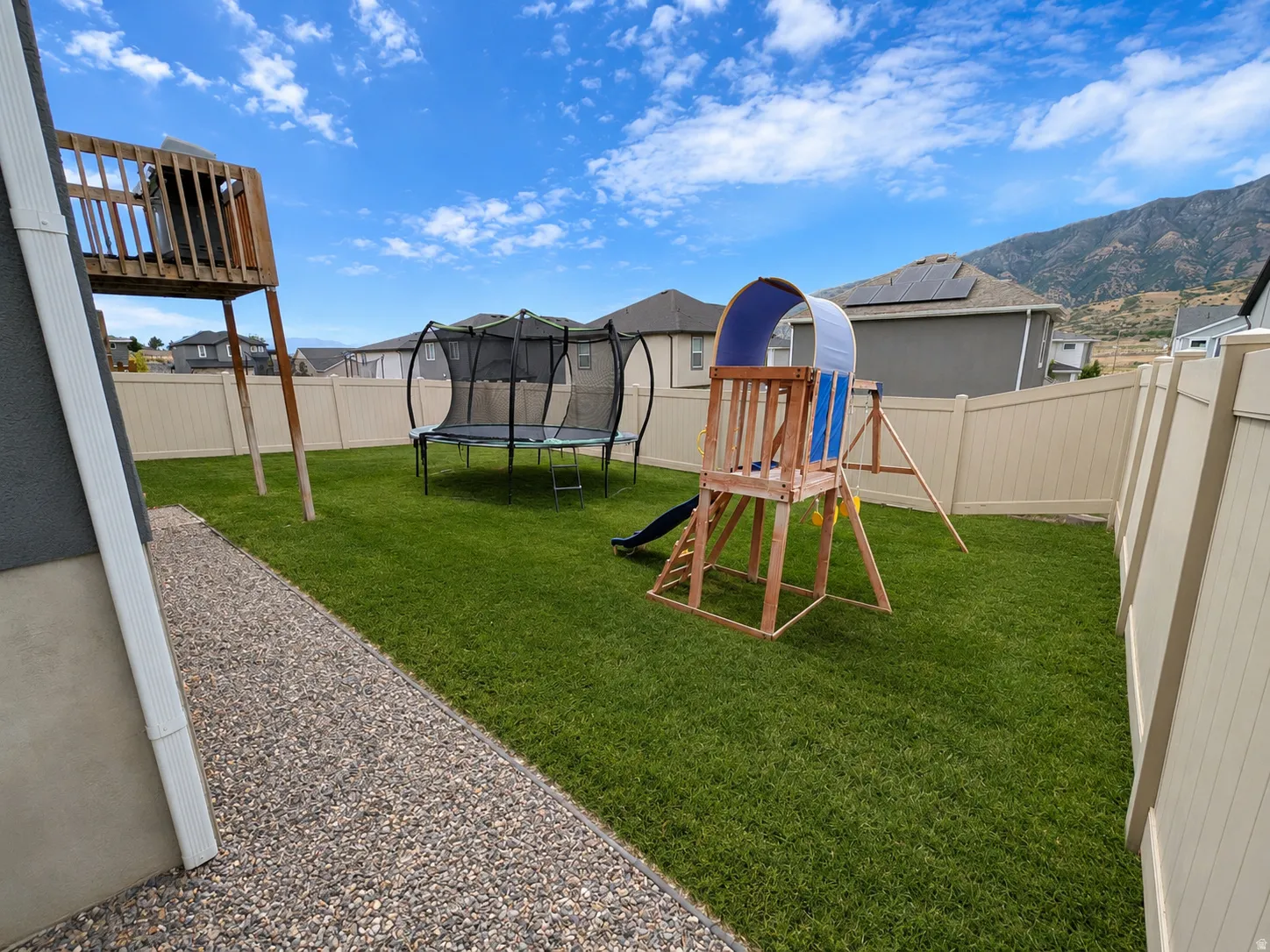 Expansive grassy backyard featuring a gravel walkway and full perimeter fencing