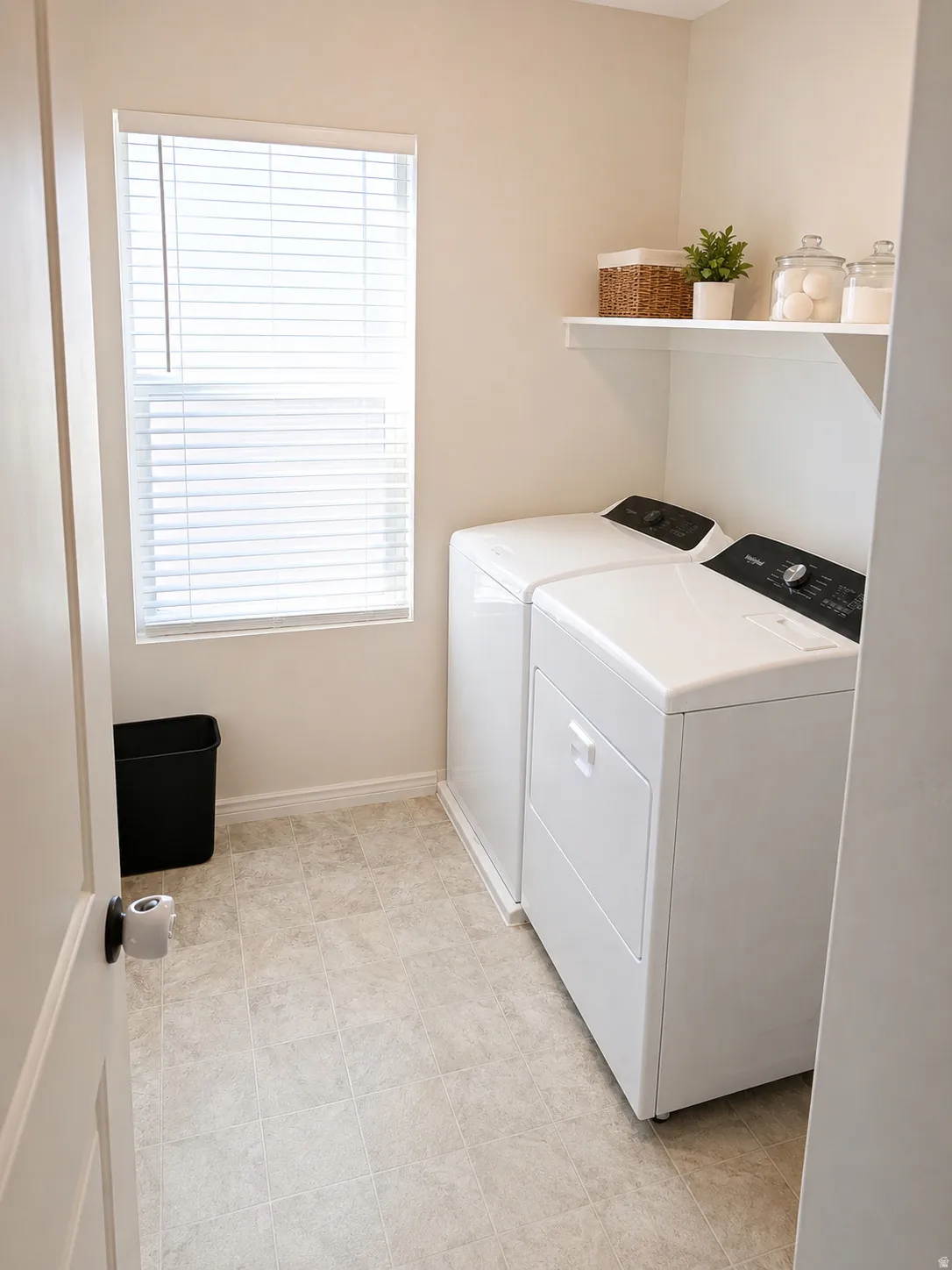Dedicated laundry area with light-toned wall paint and square-patterned flooring