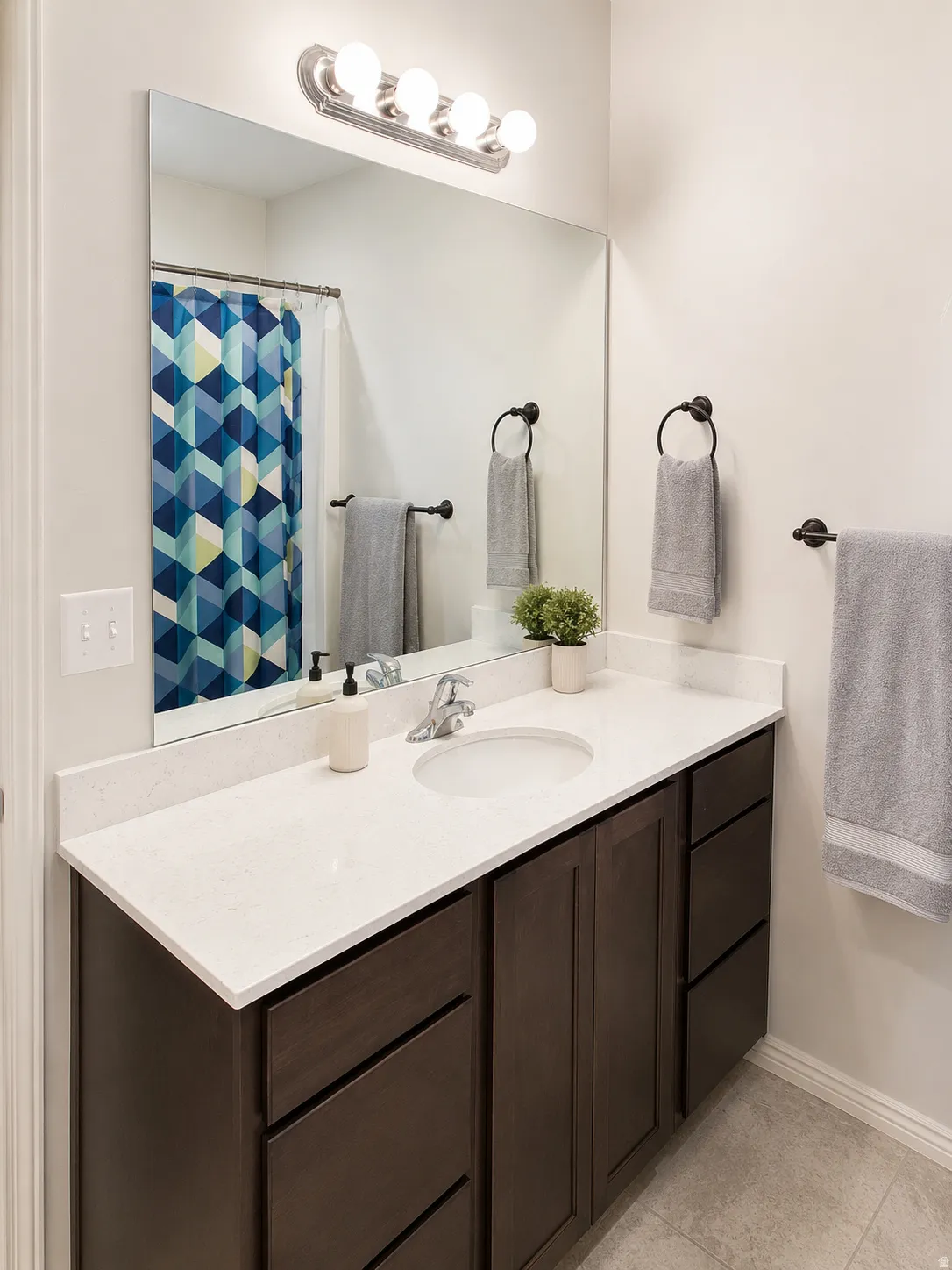 Bathroom vanity featuring a light-toned countertop, undermount sink, and dark wood-finish cabinetry