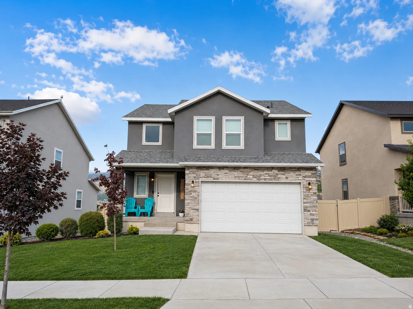 Two-story residence featuring a gray stucco exterior and a stone facade accent