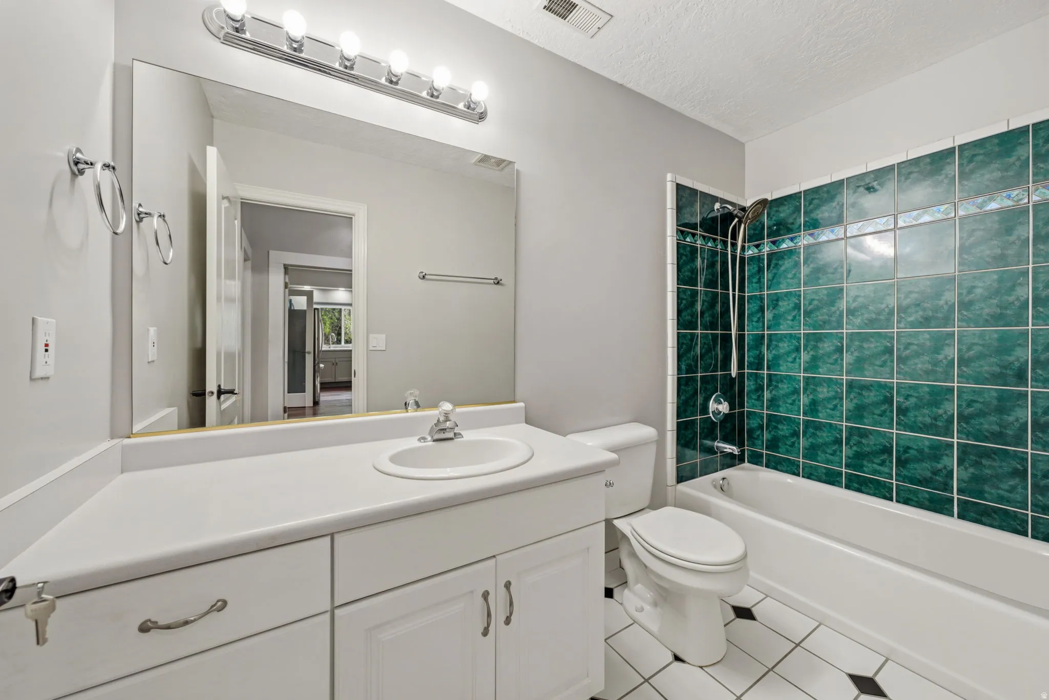 Bathroom featuring a white vanity with integrated sink, a large mirror, and a five-bulb vanity light fixture