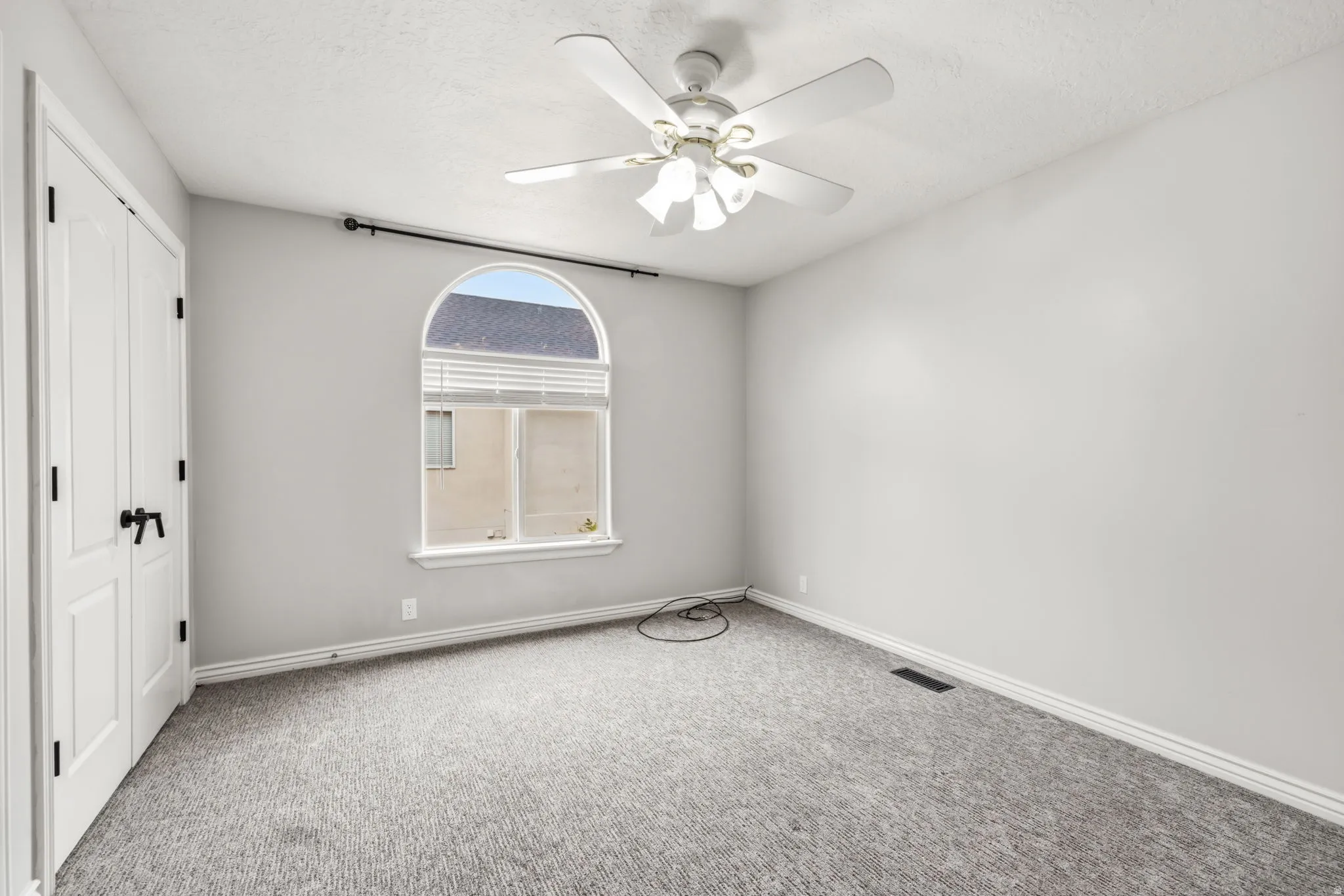 Room featuring a half-round top window, ceiling fan, and light gray wall finish