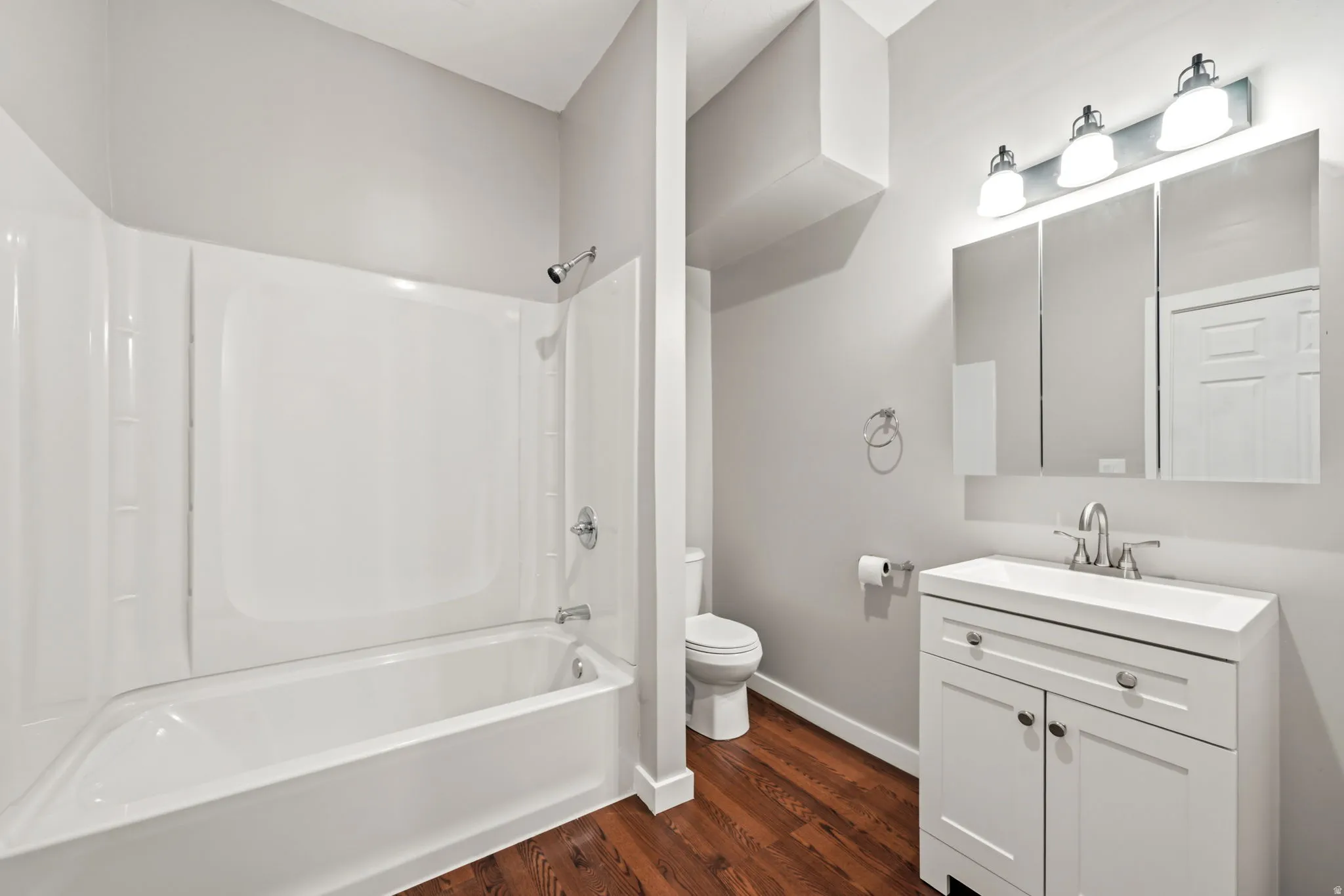 Contemporary bathroom featuring a white vanity with integrated sink, chrome faucet, and a tri-fold mirrored medicine cabinet