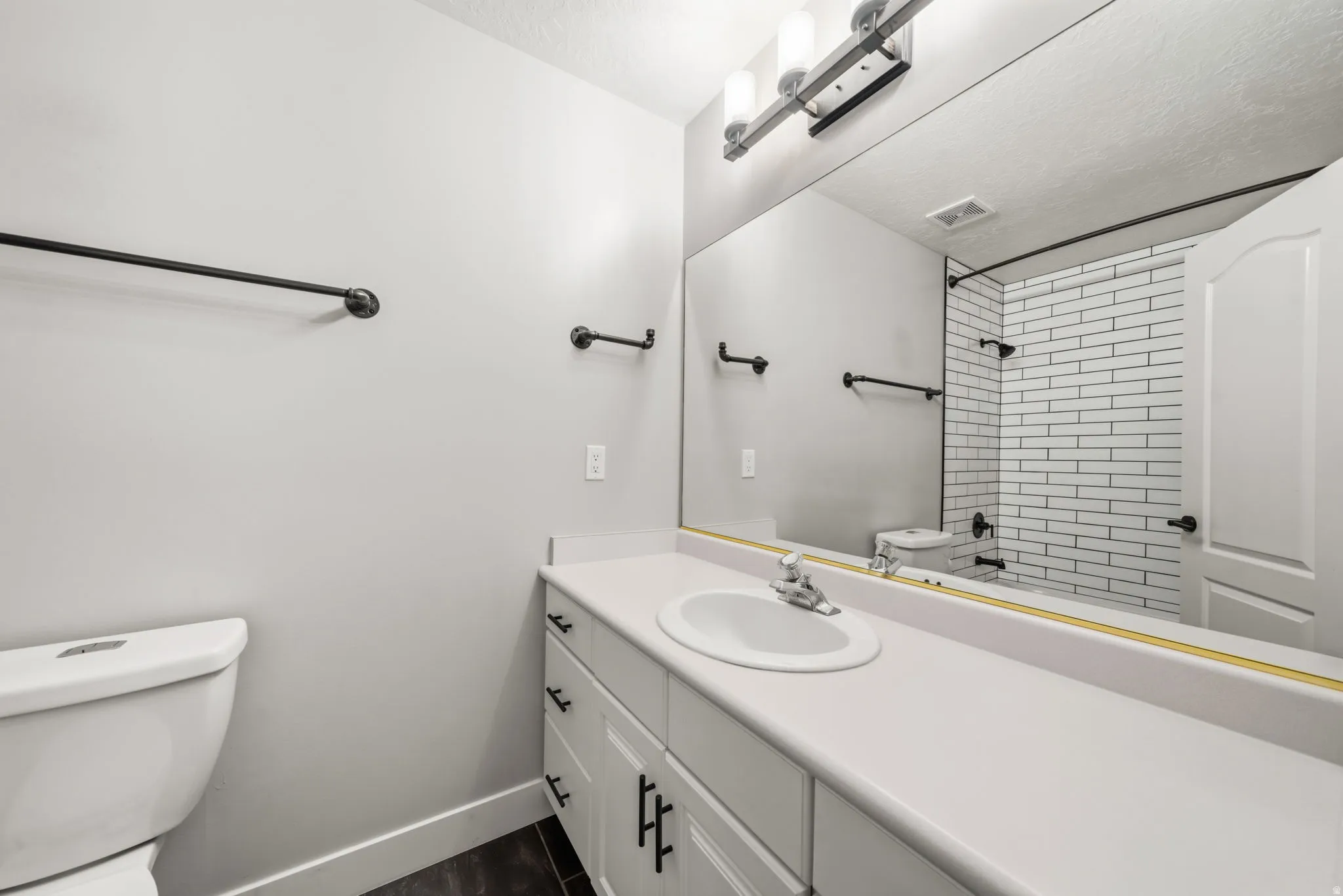 White vanity with integrated sink, white countertop, and dark-finish hardware