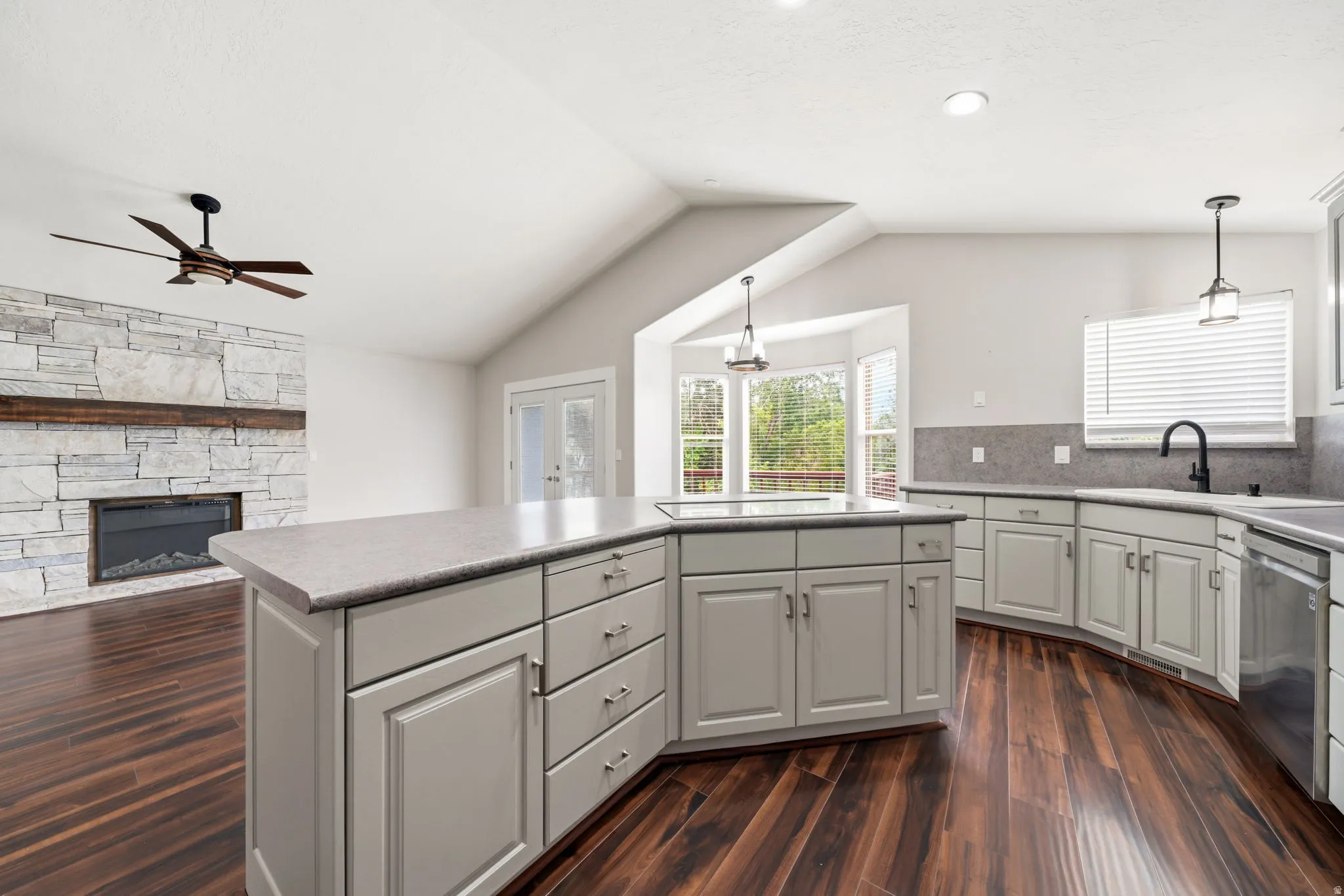 Kitchen island with light gray cabinetry and integrated cooktop, complemented by dark wood-finish flooring